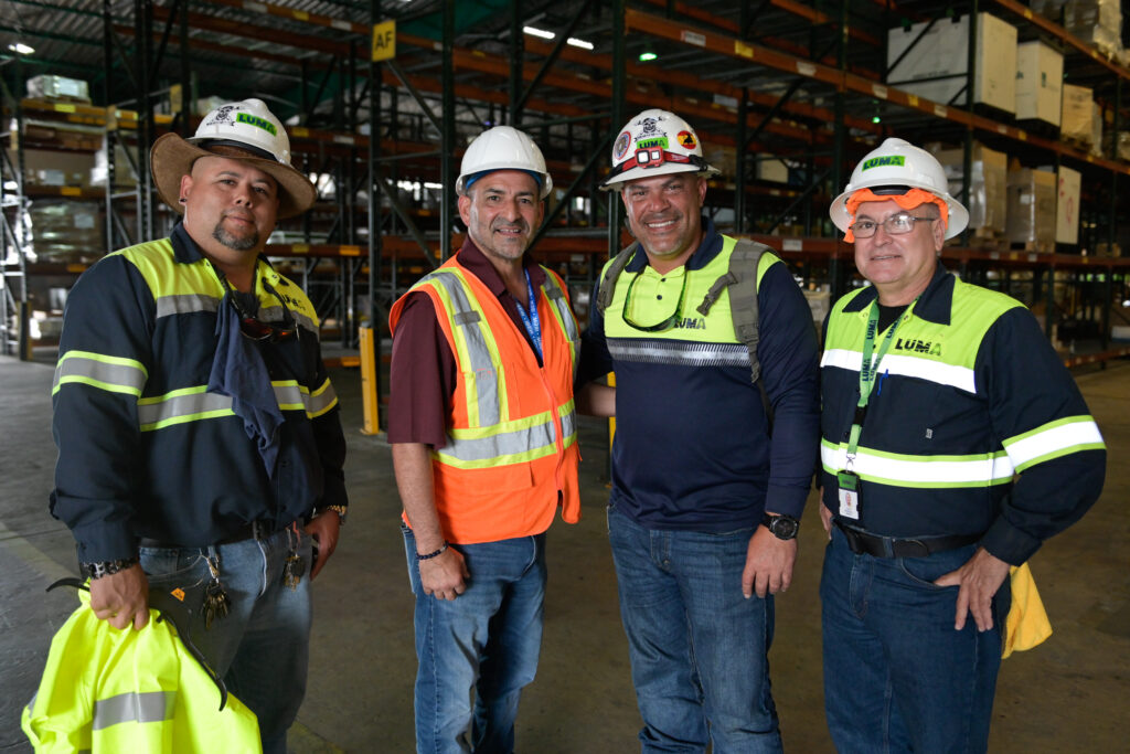 Hector Reyes (C in orange) with Omar Martinez (R) and Francisco Barrios (2nd R). New members of IBEW Local 787 at LUMA's Palo Seco warehouse in Puerto Rico.